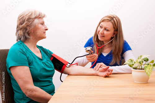 Photo: Pflegerin misst Seniorin den blutdruck Pflegerin misst Seniorin den blutdruck