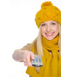 Happy girl in autumn clothes using tv remote control
