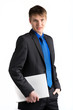 Foto: Junger Berufsstarter steht mit einem Laptop unter dem Arm vor ei Junger Berufsstarter steht mit einem Laptop unter dem Arm vor ei