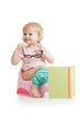 baby girl sitting on chamberpot with book