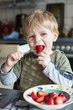 Little boy eating fresh strawberries