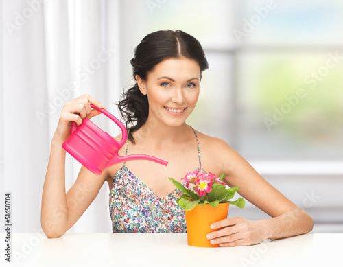 Photo: housewife with flower in pot and watering can housewife with flower in pot and watering can
