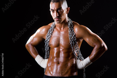 Photo: Muscular man with chain on black background Muscular man with chain on black background