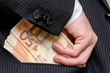 Business man putting bribe money in his jacket pocket.