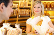Baker's shop shopkeeper gives bread to customer