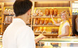 Shopkeeper in baker's shop with customer