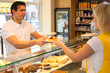 Shopkeeper giving pastry to customer