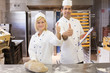 Two bakers with thumbs up in bakery