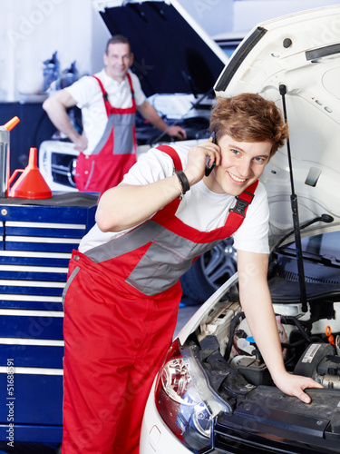 Photo: Car mechanic is satisfied with his job calling a customer Car mechanic is satisfied with his job calling a customer