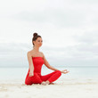 Pretty woman doing yoga exercises on the beach