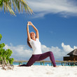 Pretty woman doing yoga exercises on the tropical beach