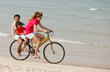 Asian sons and mother riding bicycle on beach