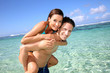 Man giving piggyback ride to girlfreind in Caribbean sea