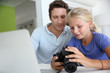 Father and daughter looking at digital camera and laptop