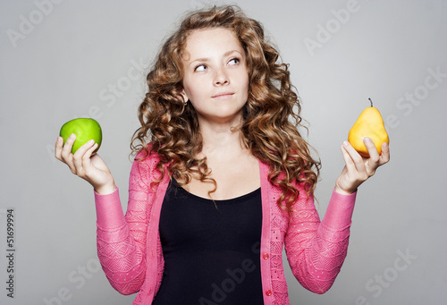 Photo: Young pretty woman holding an apple and a pear Young pretty woman holding an apple and a pear