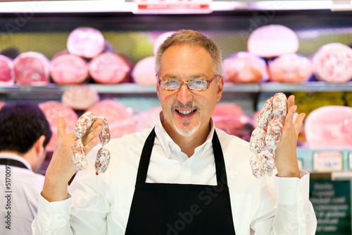 Photo: Man showing a salami in a grocery store Man showing a salami in a grocery store