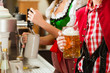Junge Frau in Tracht zapft ein Bier im Restaurant