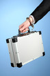 Hand with handcuff and suitcase, on color background