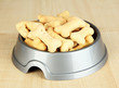 Dry dog food in bowl on wooden background