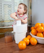 Baby girl adding orange to juicer