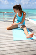 Photo: Brunette girl doing stretching exercises by the pool Brunette girl doing stretching exercises by the pool
