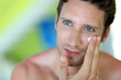 Handsome man applying moisturizing cream