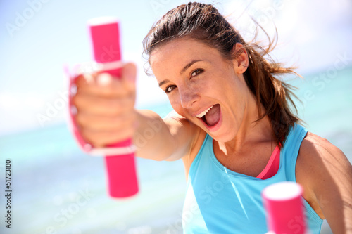 Photo: Cheerful girl lifting weights Cheerful girl lifting weights
