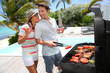 Cheerful couple in holidays preparing grilled meat