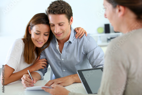 Photo: Couple signing real-estate contract Couple signing real-estate contract
