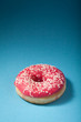 Photo: donut with red icing isolated on blue background with copyspace donut with red icing isolated on blue background with copyspace