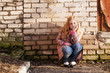 Sad Girl sitting alone near grunge wall