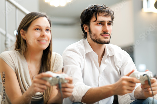 Photo: Couple playing video games on the sofa at home Couple playing video games on the sofa at home