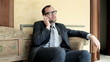 Businessman sitting on bench in antique hotel using mobilephone,