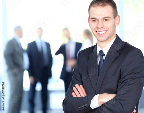 Photo: Handsome happy businessman with colleagues at the back Handsome happy businessman with colleagues at the back