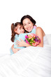 Foto: Child gives flowers to mother in bed Child gives flowers to mother in bed