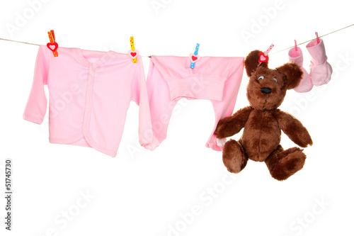 Photo: Baby clothes hanging on clothesline, isolated on white Baby clothes hanging on clothesline, isolated on white