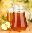 Full glass and jug of apple juice and apples