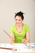 Beautiful young woman painter at work, on color background