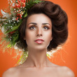 A beautiful girl with flowers on her head on an orange backgroun
