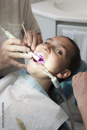Photo: Dentist finishing dental examination with ultraviolet light Dentist finishing dental examination with ultraviolet light