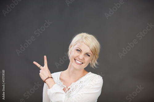 Photo: lachende blonde frau zeigt zwei finger lachende blonde frau zeigt zwei finger