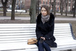 Beautiful young city woman sits on a bench