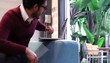 Hispanic man in indoor/outdoor creative space typing on laptop