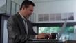 Hispanic businessman typing at laptop then turning to regard camera