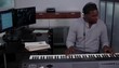 Young man wearing headphones at music station playing electronic keyboard