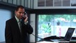 Businessman at counter with laptop conversing on telephone
