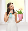 woman holding pot with flower and spray bottle