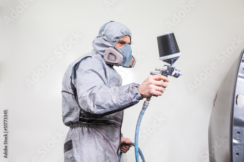 Car body painter spraying paint on bodywork parts