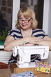 Old woman sews on the sewing machine