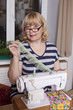 Old woman sews on the sewing machine